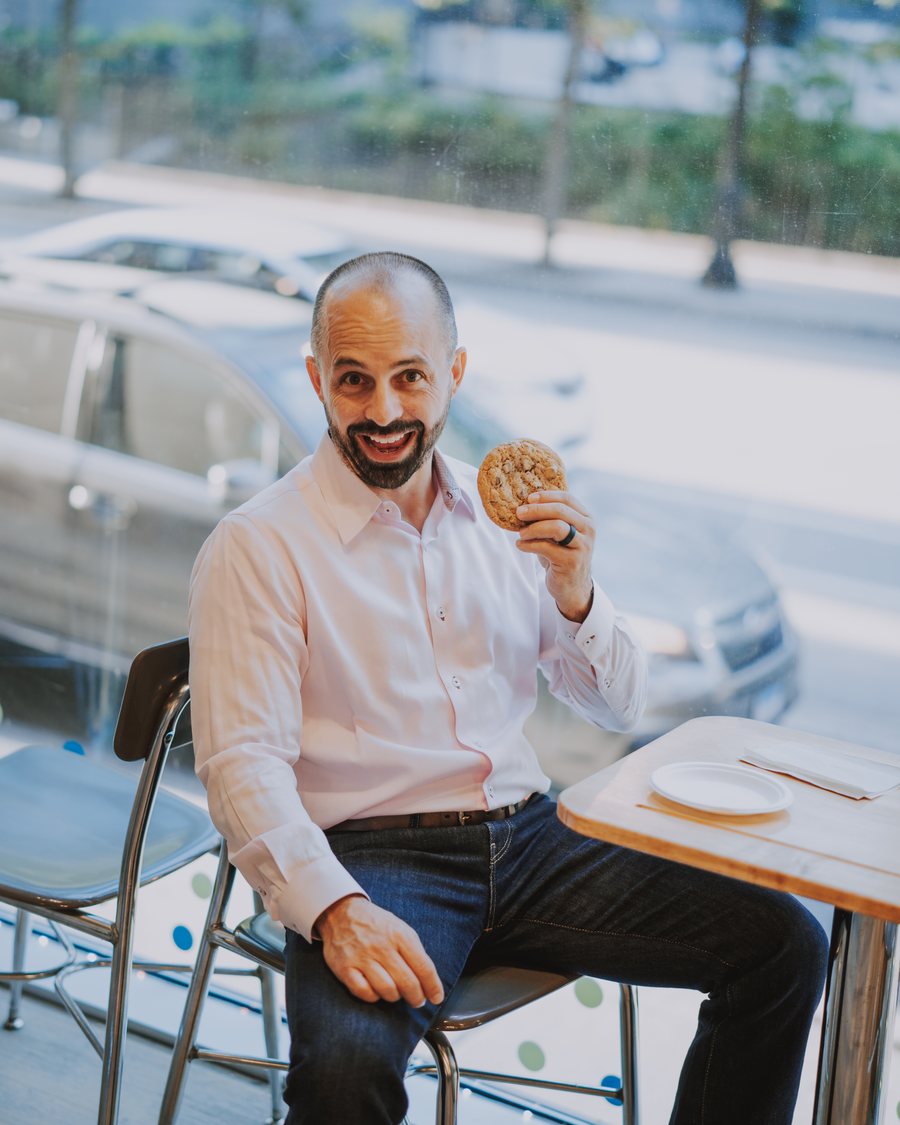 Jim Ellis holding up a cookie at a cafe table